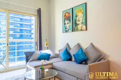 a living room with a couch with blue pillows at Alluring 1BR Opp to JBR Beach- Marina Views in Dubai