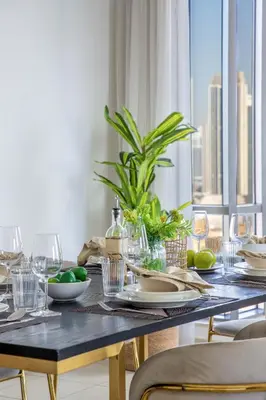 a dining room table with a table cloth and glasses and a plant at Frank Porter - South Ridge 6 in Dubai