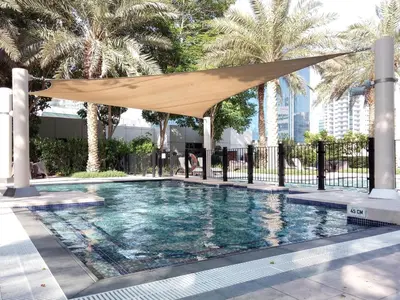 a swimming pool with a tan umbrella over it at Frank Porter - South Ridge 6 in Dubai