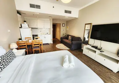 a bedroom with a large white bed and a living room at RH- Contemporary & Comfortable, Studio near Dubai mall in Dubai
