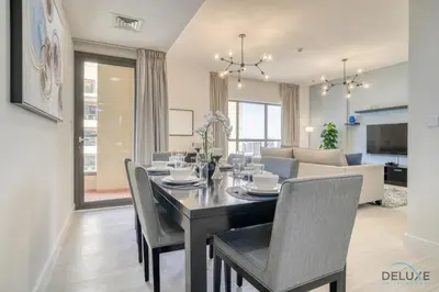a dining room and living room with a table and chairs at Exquisite 2BR At Shams 1 JBR by Deluxe Holiday Homes in Dubai