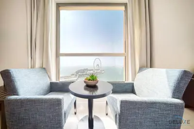 a living room with two chairs and a table and a window at Exquisite 2BR At Shams 1 JBR by Deluxe Holiday Homes in Dubai