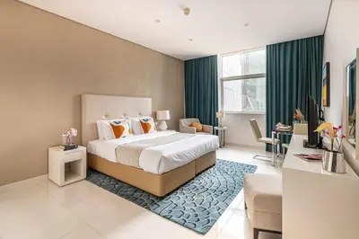 a bedroom with a large bed with a blue rug at Frank Porter - Damac Cour Jardin in Dubai