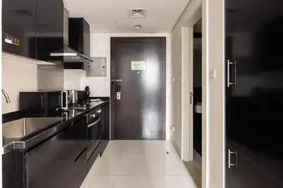 a kitchen with black cabinets and a black door at Frank Porter - Damac Cour Jardin in Dubai