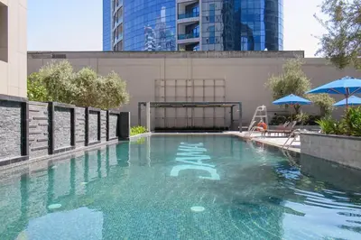 a swimming pool with blue umbrellas on a building at Frank Porter - Damac Cour Jardin in Dubai