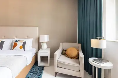 a bedroom with a bed and a chair and a window at Frank Porter - Damac Cour Jardin in Dubai