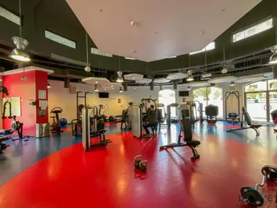 a gym with treadmills and ellipticals on a red floor at Stylish 2BR At Shams 1 JBR by Deluxe Holiday Homes in Dubai