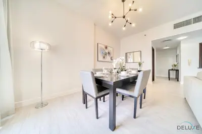 a dining room and living room with a table and chairs at Stylish 2BR At Shams 1 JBR by Deluxe Holiday Homes in Dubai