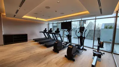 a gym with cardio equipment in a room with windows at STAY BY LATINEM Luxury 1BR Holiday Home CVR A1513 near Burj Khalifa in Dubai