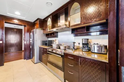 a kitchen with wooden cabinets and stainless steel appliances at Durrani Homes - Alluring 5BR Penthouse with Burj Khalifa and Fountain View in Dubai