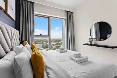 a bedroom with a white bed with a large window at Silkhaus luxurious 1BDR in new tower with pool & gym in Dubai