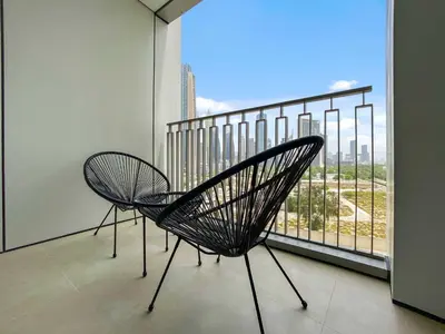 two chairs on a balcony with a view of a city at Silkhaus modern & chic 1BDR in new tower with pool & gym in Dubai