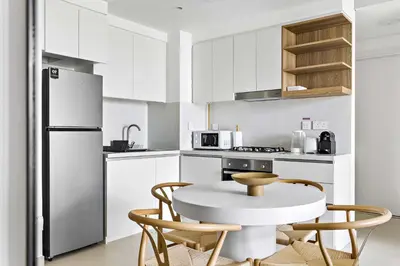 a kitchen with a table and chairs and a refrigerator at Silkhaus modern & chic 1BDR in new tower with pool & gym in Dubai