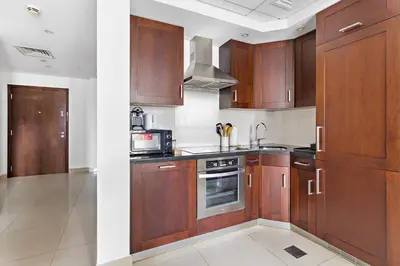 a kitchen with wooden cabinets and a stove at Silkhaus beautiful studio in Downtown near Burj Khalifa in Dubai