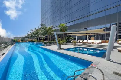 a large swimming pool next to a tall building at FAM Living - Palm Tower Attached to St Regis Palm Tower 1Bed - Palm Jumeirah Views in Dubai
