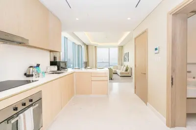 a kitchen with wooden cabinets and a living room at FAM Living - Palm Tower Attached to St Regis Palm Tower 1Bed - Palm Jumeirah Views in Dubai