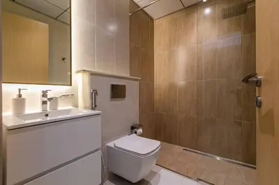 a bathroom with a toilet and a sink and a shower at Stunning 1 Bedroom Apartment - Regina Tower - JVC in Dubai