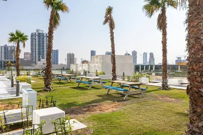 a park with picnic tables and palm trees in a city at Stunning 1 Bedroom Apartment - Regina Tower - JVC in Dubai