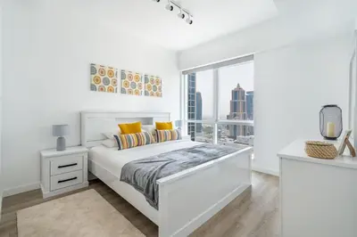 a white bedroom with a white bed and a window at GuestReady - Moment in time at Al Majara in Dubai