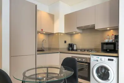 a kitchen with a glass table and a dishwasher at 10min from Burj Khalifa - Sobha Creek Vistas Réservé in Dubai