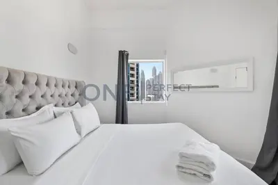 a white bedroom with a large bed and a window at Stunning Lake View - Height Floor - Furnished 1BR in Dubai