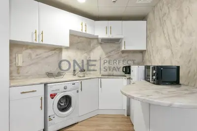 a white kitchen with a washer and dryer at Stunning Lake View - Height Floor - Furnished 1BR in Dubai
