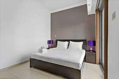 a bedroom with a large white bed with purple lamps at 3-5 mins walk to JBR 5-7 mins to the tram in Dubai