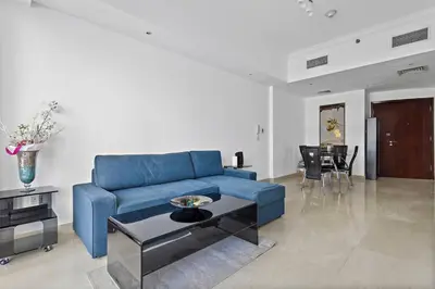 a blue couch in a living room with a table at 3-5 mins walk to JBR 5-7 mins to the tram in Dubai