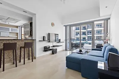 a living room with a blue couch and a kitchen at 3-5 mins walk to JBR 5-7 mins to the tram in Dubai
