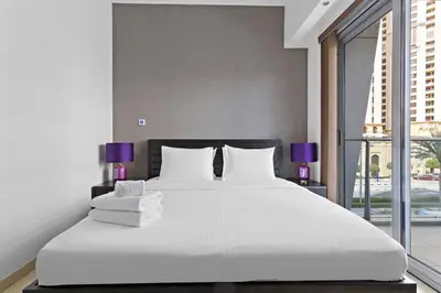 a bedroom with a large bed with white sheets and purple lamps at 3-5 mins walk to JBR 5-7 mins to the tram in Dubai
