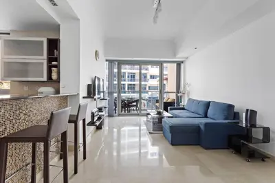 a living room with a blue couch and a kitchen at 3-5 mins walk to JBR 5-7 mins to the tram in Dubai