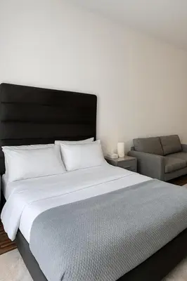 a bedroom with a large bed and a chair at Cozy Apartment in Jumeirah Village Circle, Dubai. in Dubai