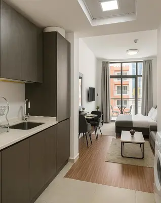 a kitchen and living room with a couch and a table at Cozy Apartment in Jumeirah Village Circle, Dubai. in Dubai