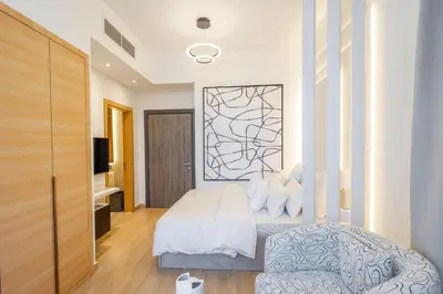 a bedroom with a white bed and a tv at Le Villa-Joie !Bright Studio Apartment! in Dubai