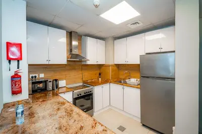 a kitchen with white cabinets and a stainless steel refrigerator at City Stay Residences - Serviced Apartments DIP in Dubai