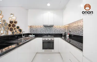 a kitchen with white cabinets and black and white tiles at Paramount 2 Bed Apt, Roof Top Bar and Pool overlooking Burj, Triple Balcony, Fully Equipped, Free Toiletries, Full Kitchen, 2 and half Bathrooms, Ground Floor Supermarket, Influencers Haven, Sunrise and Sunset Views over the Sea From All Balcony in Dubai