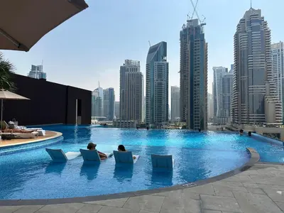 two people sitting in chairs in a pool with a city skyline at LUXURY 1 BR Apartment at Marina Gate Jumeirah Living in Dubai