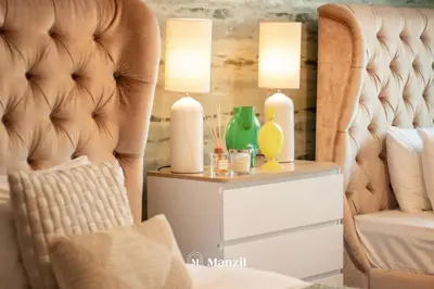 a bedroom with a chair and a side table with two lamps at Manzil - Luxury 3BR Villa w/ maid room, Full Burj & Fountain view in Dubai
