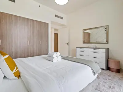 a bedroom with a large white bed and a dresser at Fantastic 1 BR in Park Point - Dubai Hills in Dubai
