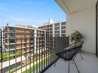 a balcony with two chairs and a view of a building at Fantastic 1 BR in Park Point - Dubai Hills in Dubai