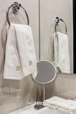 a towel rack with two white towels and a mirror at Elegant 3BR in a Prime Location Near Metro, Business Bay in Dubai