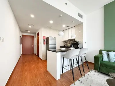 a kitchen and living room with a green couch at Trophy - Urban Oasis Suite in Dubai