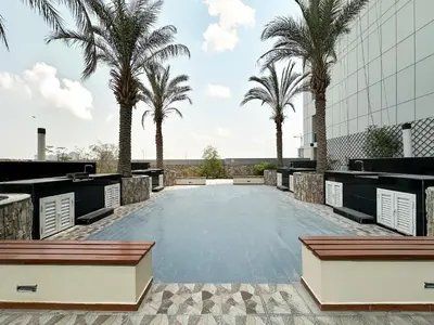 a large pool with palm trees and a building at Trophy - Urban Oasis Suite in Dubai