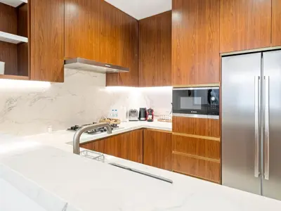 a kitchen with wooden cabinets and a stainless steel refrigerator at Elegant Apartment Amidst Vibrant Area With Balcony in Dubai