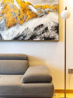 a painting hanging on a wall next to a couch at Elegant Apartment Amidst Vibrant Area With Balcony in Dubai