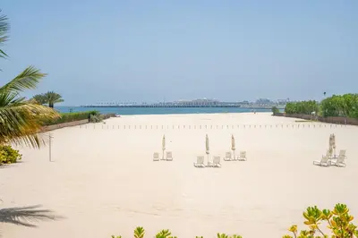 a beach with chairs and a pier in the background at GuestReady - Beachfront heaven with stunning views in Dubai