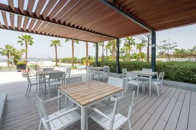 a wooden table and chairs on a deck with a pergola at GuestReady - Beachfront heaven with stunning views in Dubai