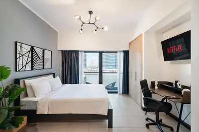 a hotel room with a bed and a desk and a window at Luxury JLT Studio Lakeview Pool & Marina Walk in Dubai