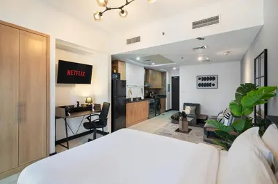 a bedroom with a white bed and a kitchen at Luxury JLT Studio Lakeview Pool & Marina Walk in Dubai