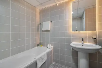 a bathroom with a tub and a sink and a mirror at Furnished studio in Arch Tower, JLT near metro in Dubai